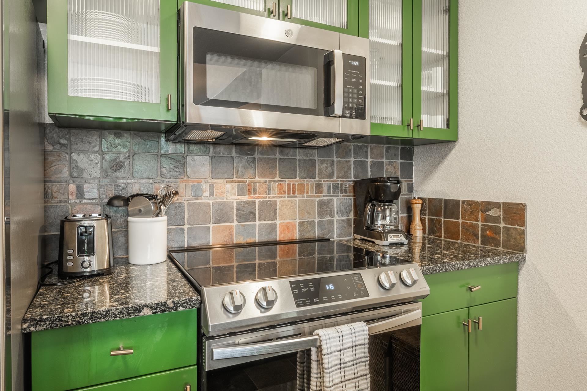 6201 Minaret Road, Unit 2221 Mammoth Lakes, CA 93546 - Photo 7 of 32 Kitchen featuring vibrant green cabinetry, textured tile backsplash, stainless steel appliances, and dark speckled countertops