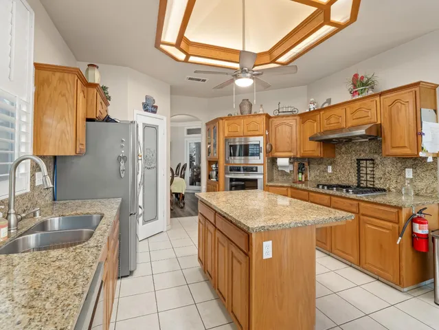 a kitchen with stainless steel appliances granite countertop a sink a stove and a wooden cabinets