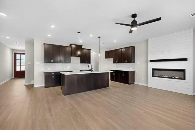 a large kitchen with stainless steel appliances wooden floor and a view of living room