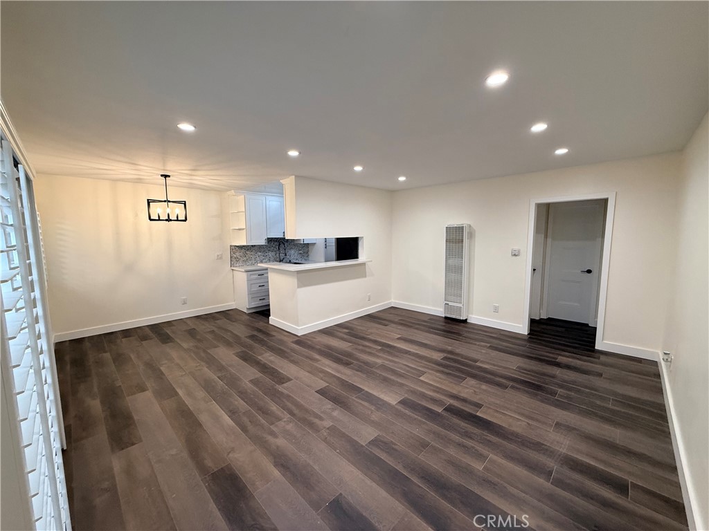 a view of kitchen and empty room with wooden floor