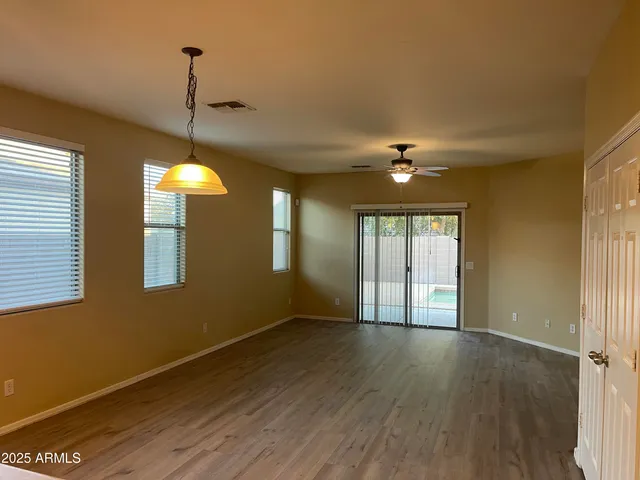 a view of an empty room with window and wooden floor