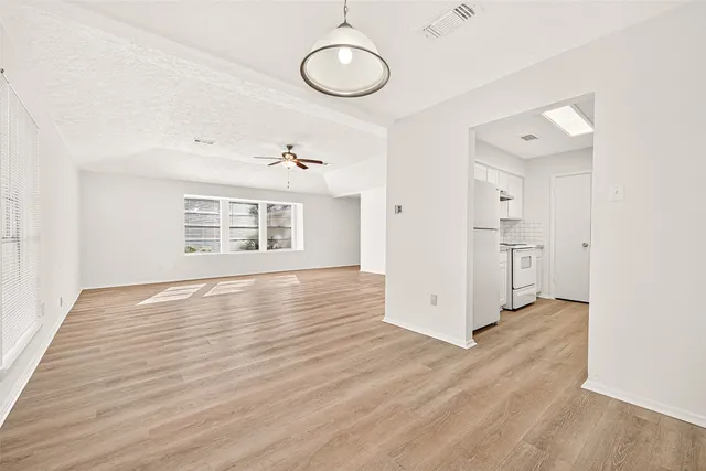 a view of an empty room with a window and wooden floor