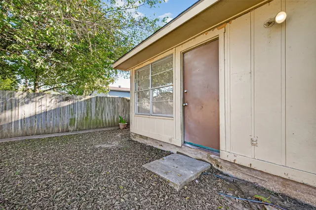 a backyard of a house with plants and large tree