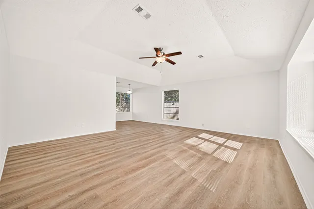 a view of a bedroom with wooden floor and a ceiling fan