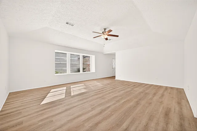 a view of an empty room with a window and wooden floor