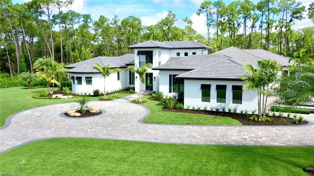 6435 Sable Ridge Lane Naples, FL 34109 - Photo 1 of 8 a front view of a house with a garden and trees