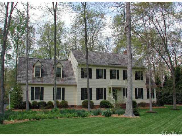 a front view of a house with garden and trees