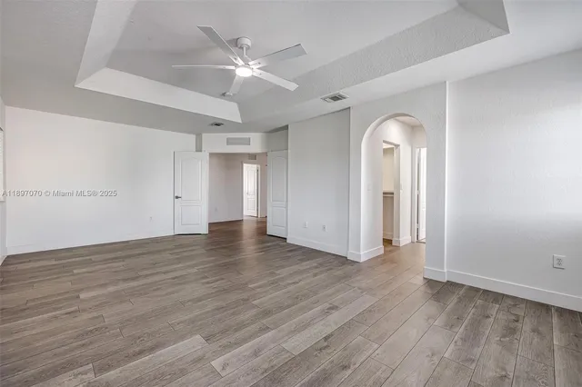 an empty room with wooden floor and fan