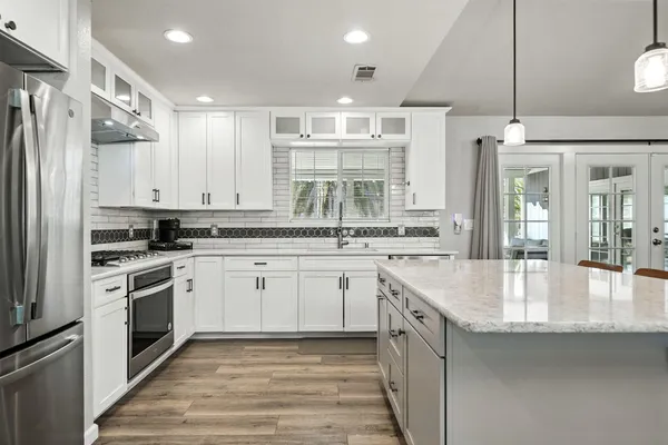 a kitchen with white cabinets appliances and a window