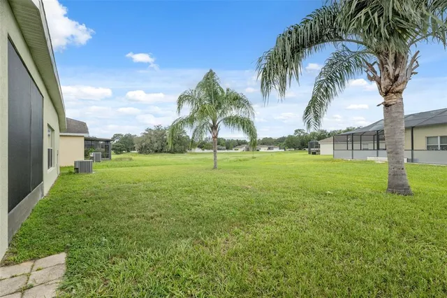 a view of a white house with a big yard and palm trees