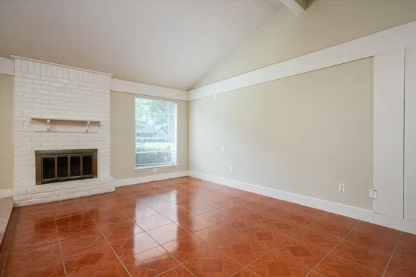 a view of an empty room with a window and fire place