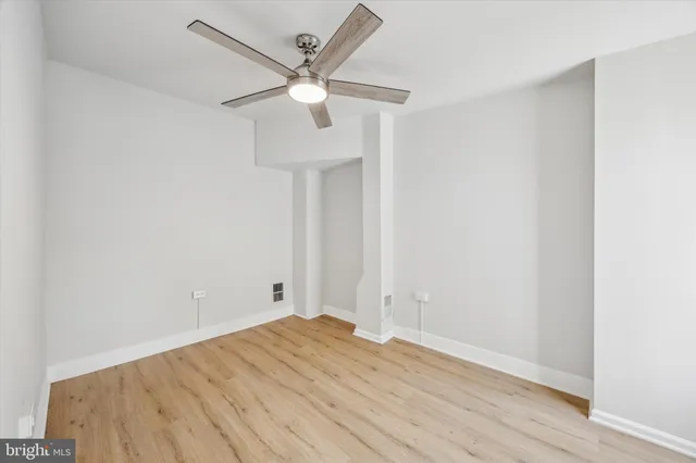 an empty room with wooden floor and a ceiling fan