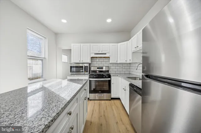 a kitchen with granite countertop a sink stove and refrigerator