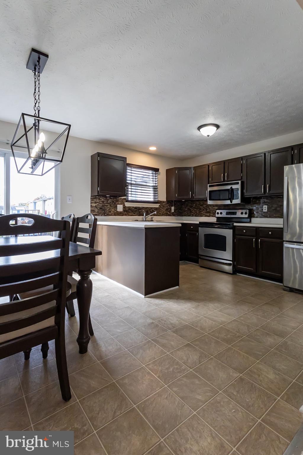 511 Kosoak Road Baltimore, MD 21220 - Photo 12 of 63 a kitchen with stainless steel appliances granite countertop a stove top oven a sink dishwasher a dining table and chairs with wooden floor