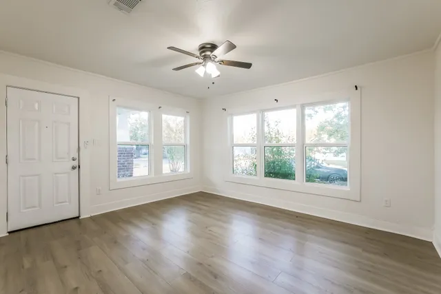 a view of an empty room with wooden floor and a window