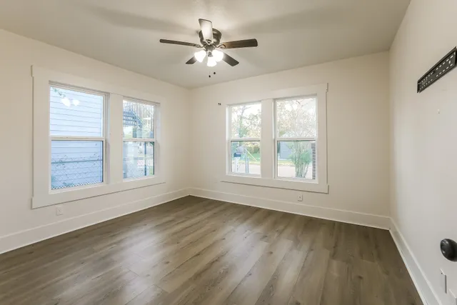 a view of an empty room with wooden floor and a window