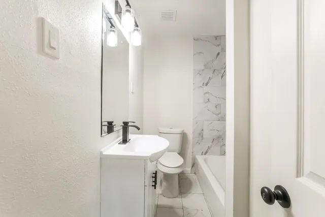 a bathroom with a sink a toilet and shower