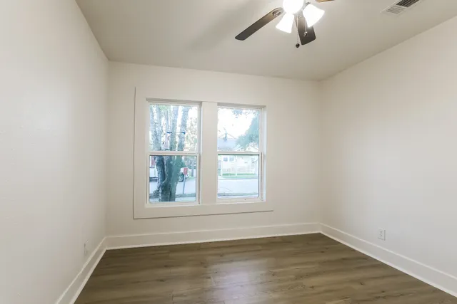 an empty room with wooden floor and windows