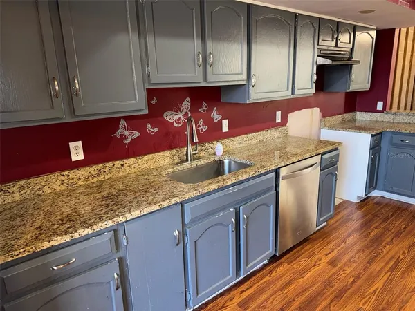 a large kitchen with kitchen island granite countertop wooden floors and a large window