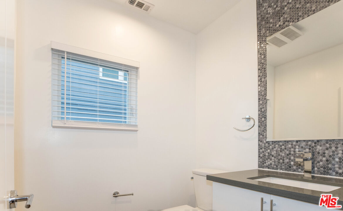 6546 La Mirada Avenue, Unit 6548 Los Angeles, CA 90038 - Photo 8 of 24 a bathroom with a granite countertop sink and a mirror