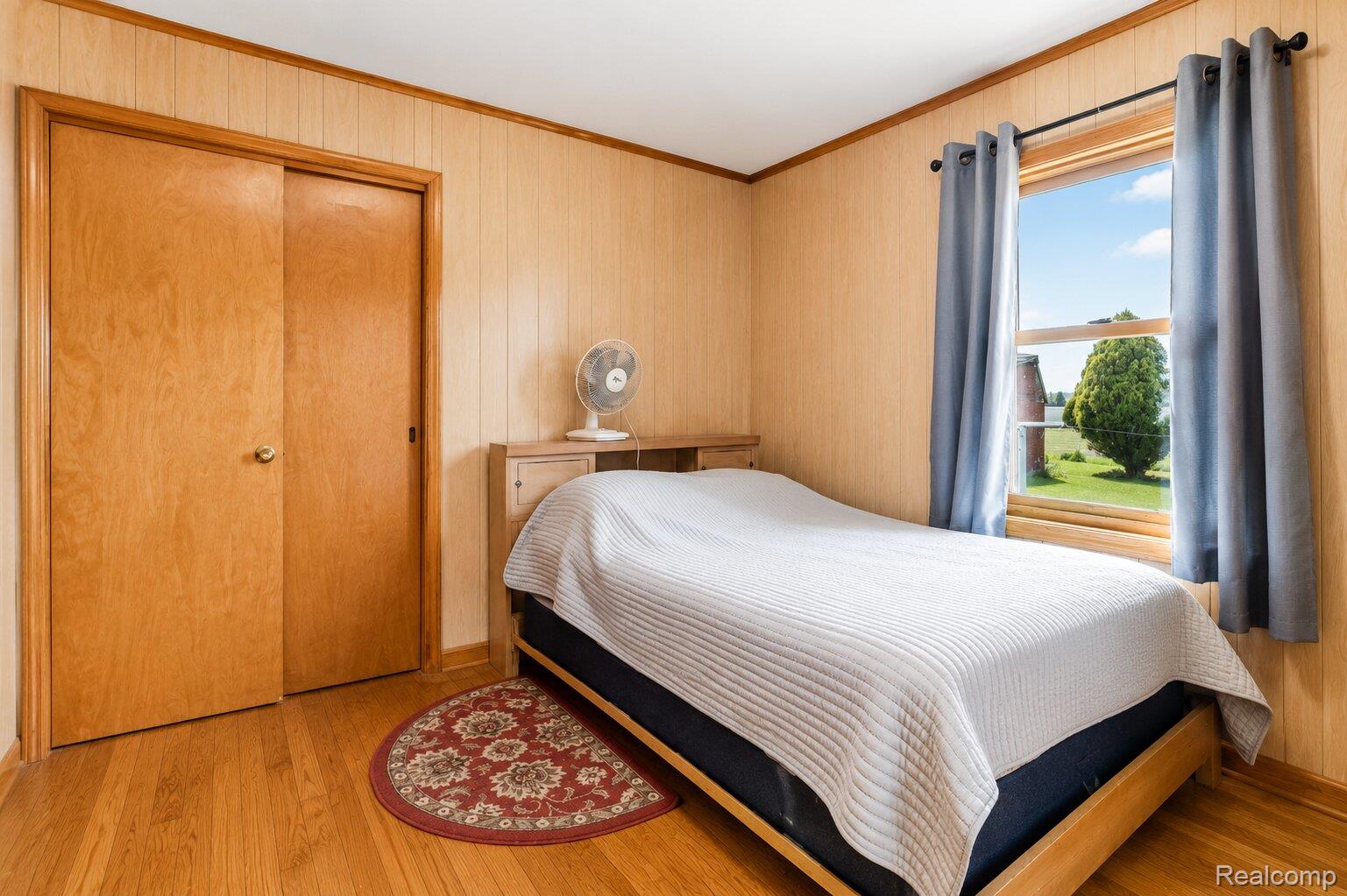 6373 Norman Road Jeddo, MI 48032 - Photo 11 of 32 Bedroom with ornamental molding, light wood-style floors, a closet, and wood walls