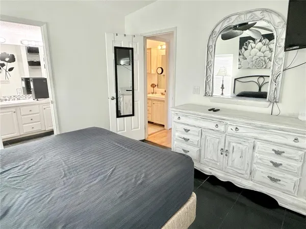 a spacious bedroom with a bed a dresser and mirror