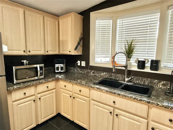 a kitchen with granite countertop white cabinets stainless steel appliances a sink and a window