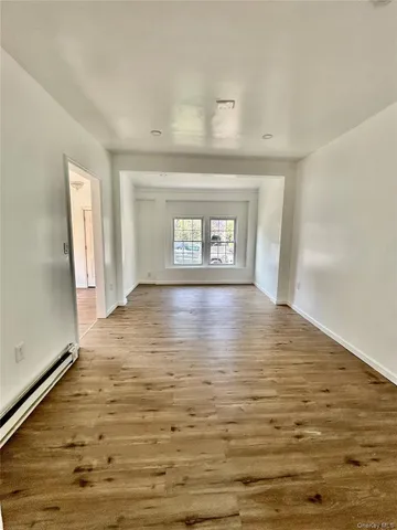 a view of empty room with window and wooden floor