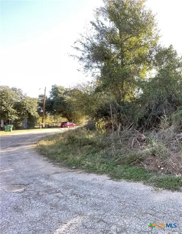 a view of dirt field with large trees