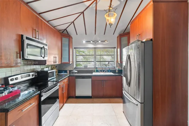 a kitchen with stainless steel appliances granite countertop a refrigerator a sink dishwasher a stove and a dining table with wooden floor