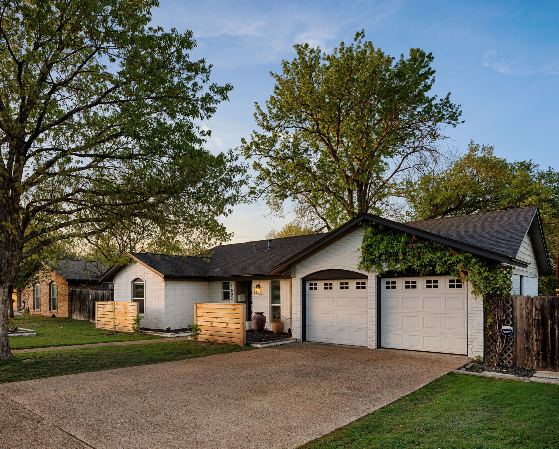 1602 Thornridge Road Austin, TX 78758 - Photo 9 of 39 Ranch-style home featuring a garage, driveway, a shingled roof, and brick siding