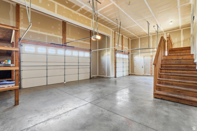 338 Windy Rdg Drive Smithfield, UT 84335 - Photo 54 of 63 Spacious garage featuring two overhead doors with window panels, concrete flooring, and an exposed wood staircase
