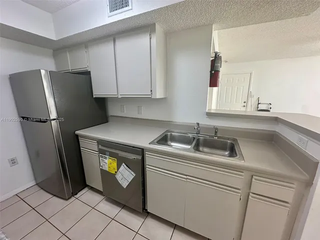 a view of a refrigerator in kitchen and an empty room