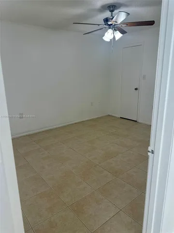 a view of an empty room with a chandelier fan