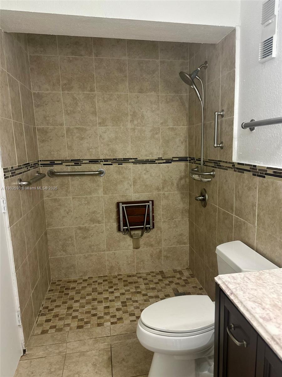 10581 Southwest 155th Court, Unit 1214 Miami, FL 33196 - Photo 22 of 35 a bathroom with a granite countertop toilet a sink and shower