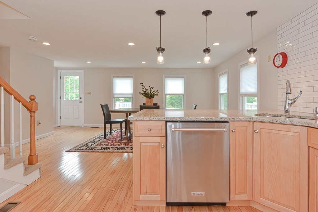 3 Zina Road Hudson, MA 01749 - Photo 12 of 41 a large kitchen with stainless steel appliances granite countertop a refrigerator a sink dishwasher a dining table and chairs with wooden floor