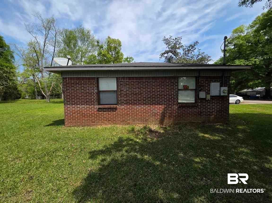 106 West 16th Street Bay Minette, AL 36507 - Photo 3 of 19 View of home's exterior with brick siding and a lawn