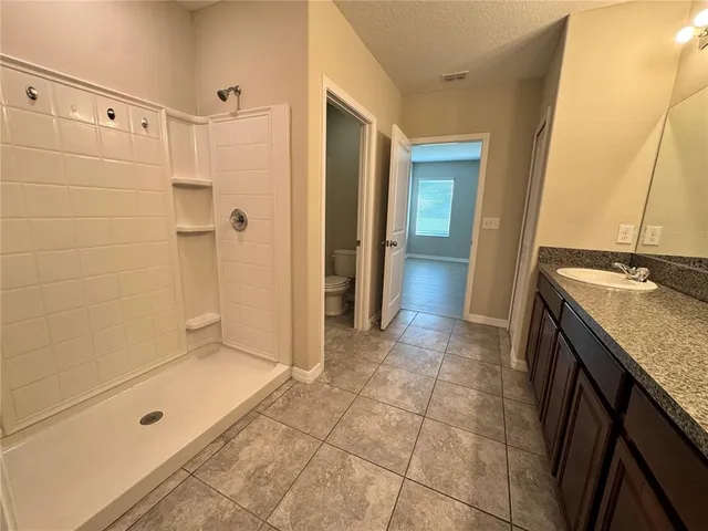 a bathroom with a granite countertop sink a mirror and shower