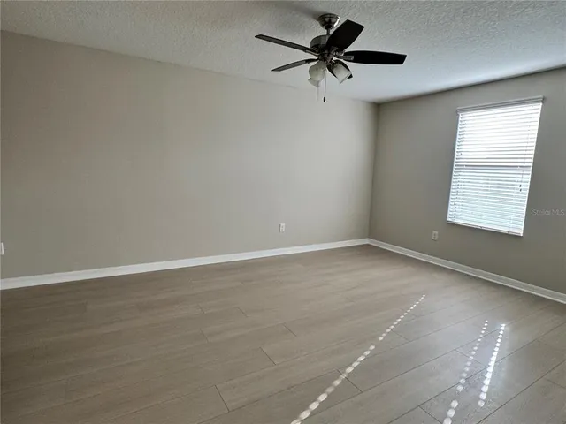 an empty room with a window and a fan