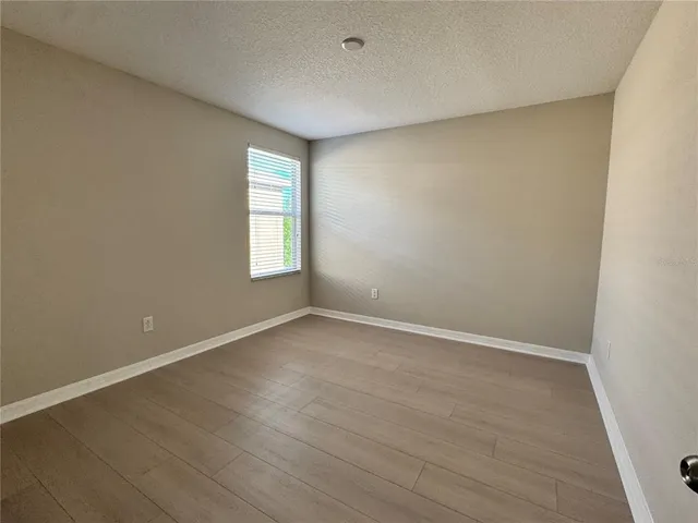 a view of an empty room with wooden floor and window