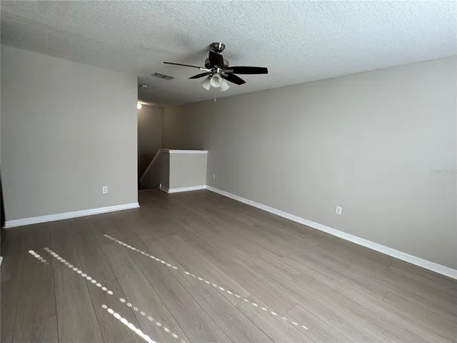 an empty room with a ceiling fan and hardwood floor