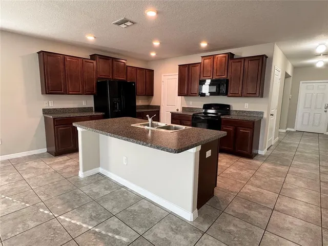 a kitchen with kitchen island granite countertop a sink a stove top oven and cabinets