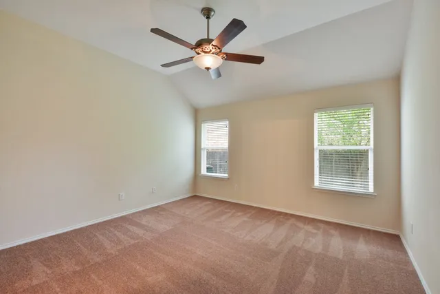 an empty room with windows and fan