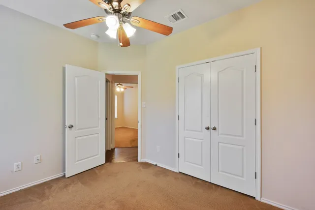 a view of an empty room and chandelier fan