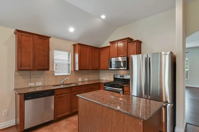 a kitchen with stainless steel appliances granite countertop a refrigerator a sink a stove a microwave and island