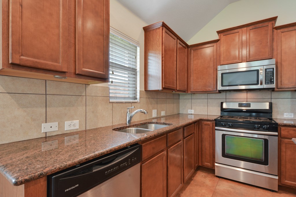 291 Cold Spring Buda, TX 78610 - Photo 6 of 25 a kitchen with granite countertop a sink stove and microwave