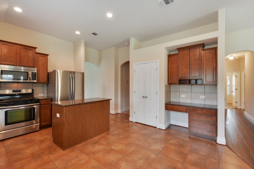 291 Cold Spring Buda, TX 78610 - Photo 9 of 25 a kitchen with stainless steel appliances granite countertop a refrigerator and a stove top oven