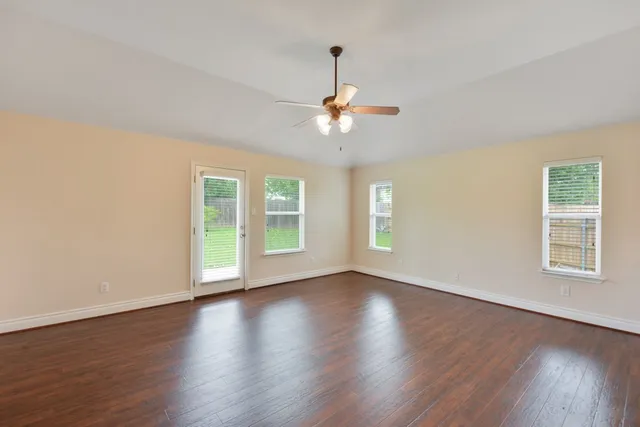 a view of an empty room with wooden floor and a window
