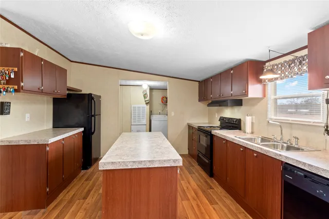 a kitchen with stainless steel appliances granite countertop a stove a refrigerator a sink dishwasher and wooden cabinets with wooden floor