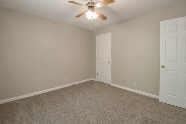an empty room with closet and a ceiling fan